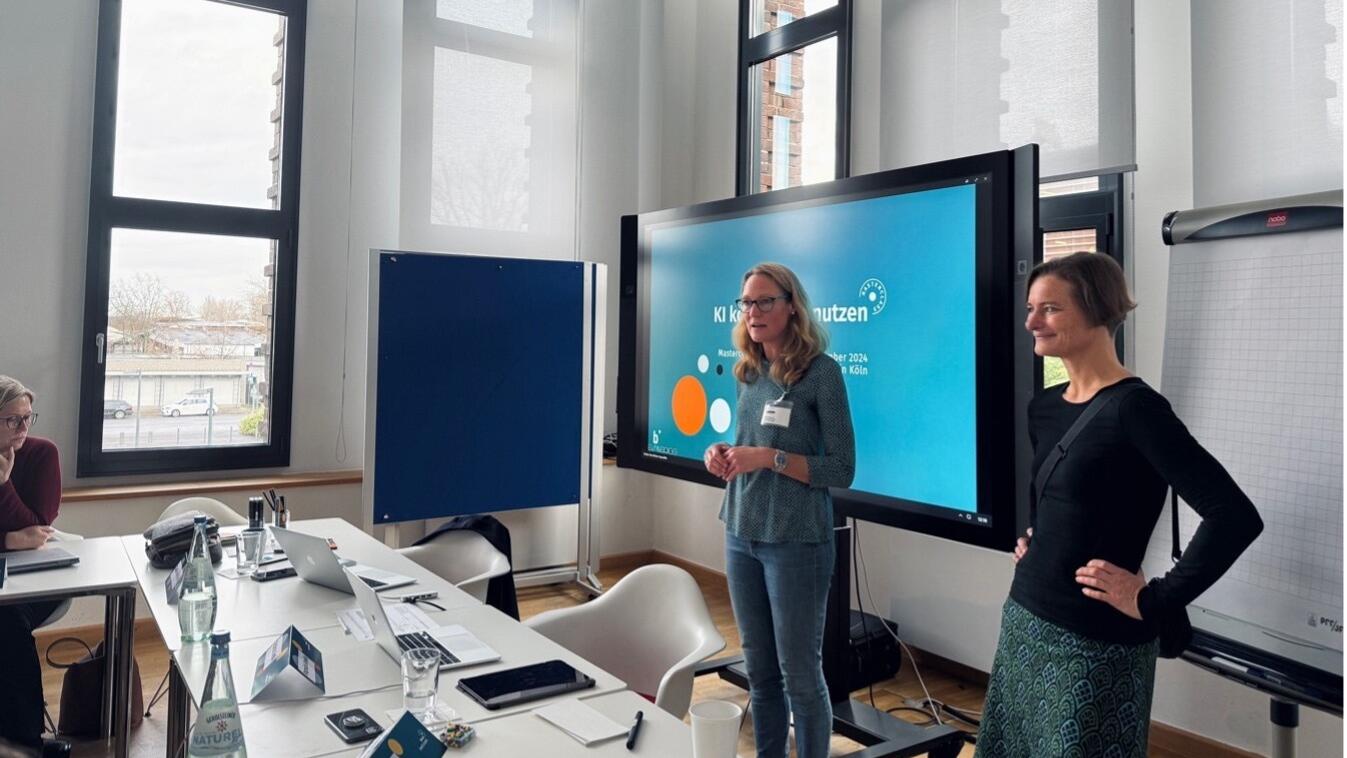 Claudia Rittel and Donata Dröge stand in front of a screen while giving a presentation on AI in journalism