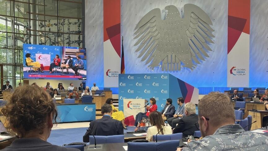 Das Bild zeigt die Opening Session des Global Media Forum 2024, zu sehen ist Ellen Heinrichs, die gerade in ein Mikrofon spricht.