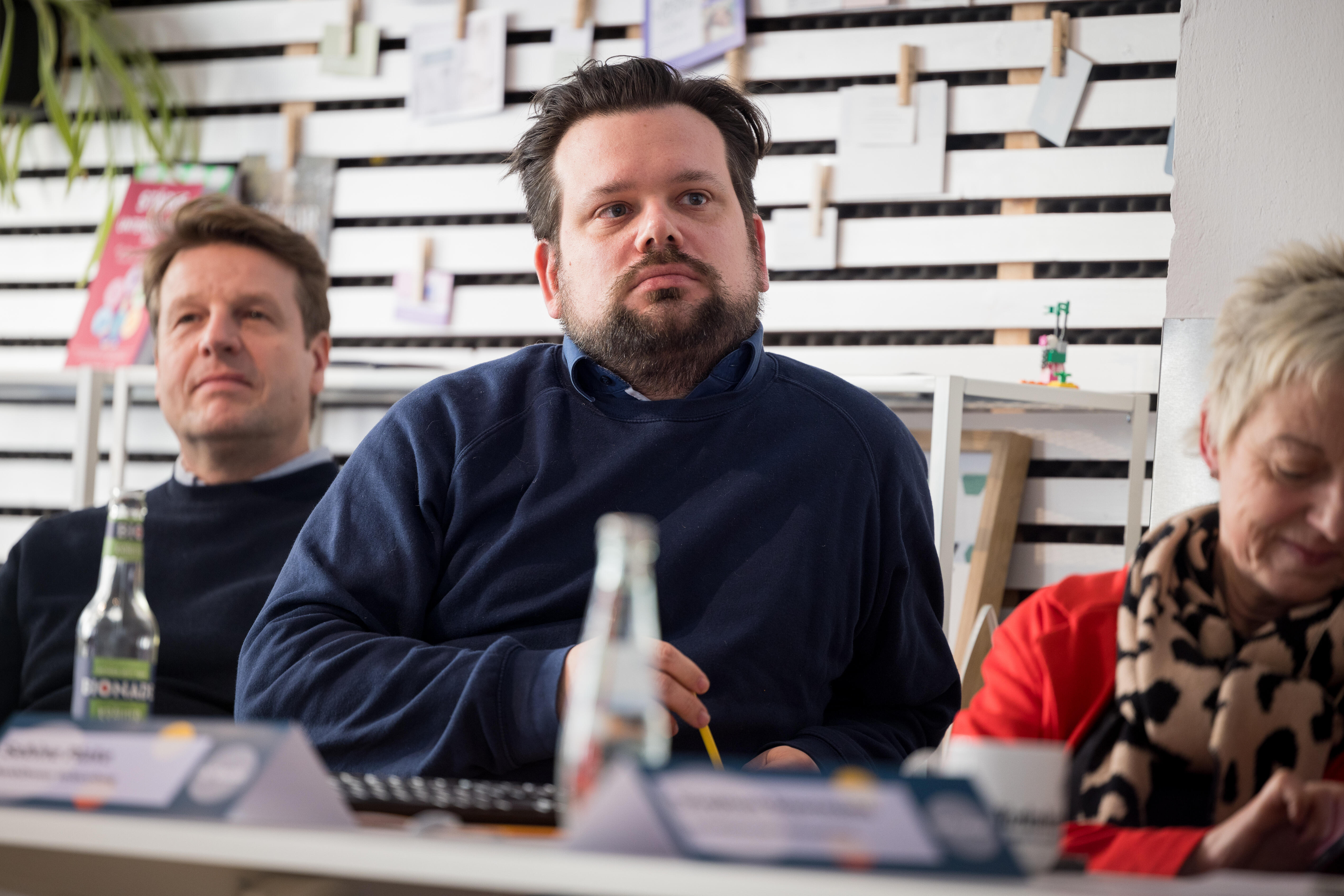 A man sits at a desk next to two other people